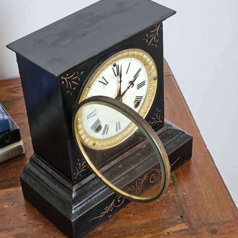 Vintage-style clock with gold and black design on a wooden surface