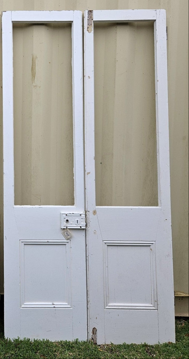 Two pairs of white French doors with glass panes and metal hardware, showing signs of wear and age.