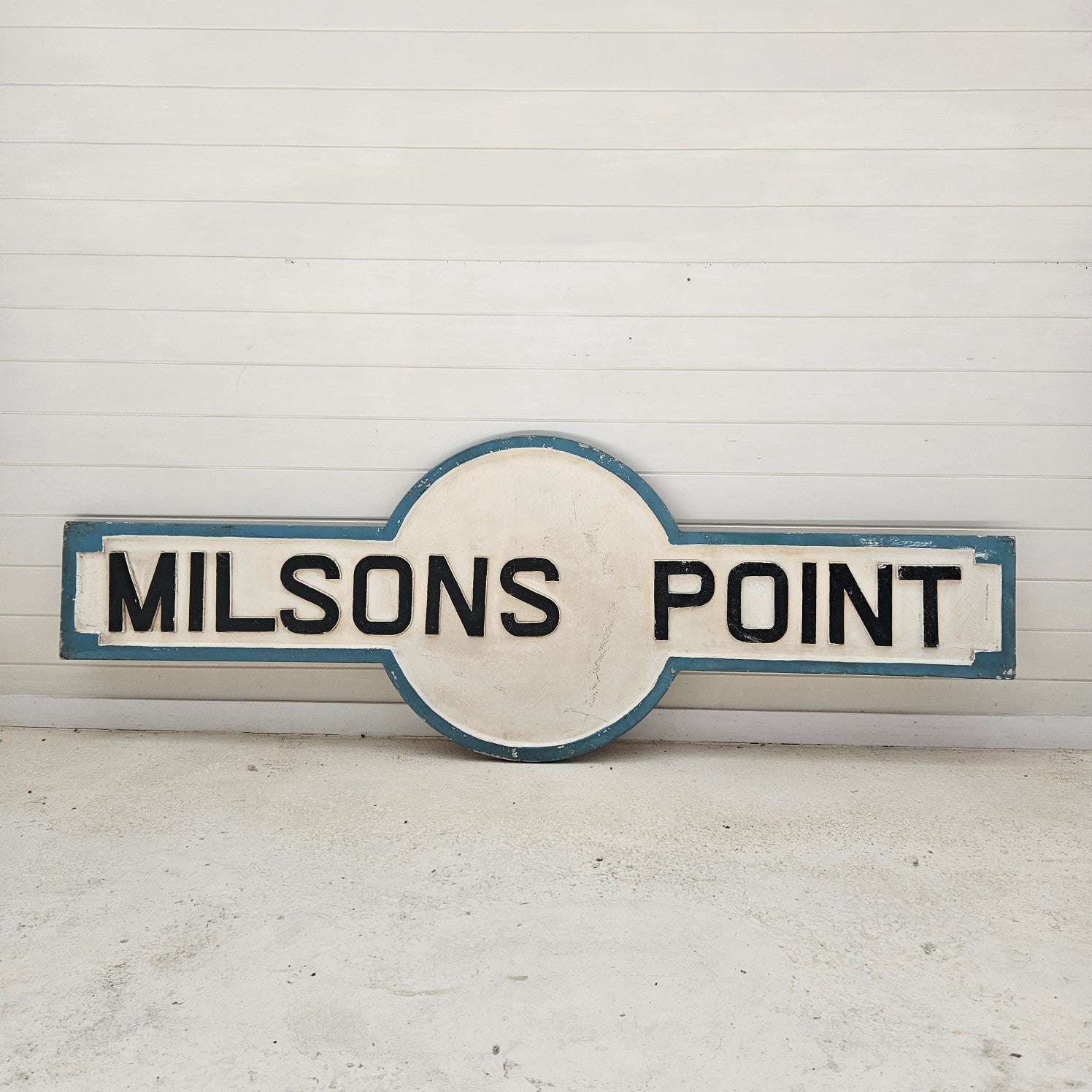 Round sign with 'MILSONS POINT' text on a white background