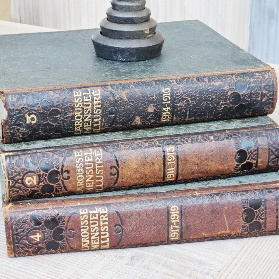 Stack of vintage books with leather bindings on a textured surface