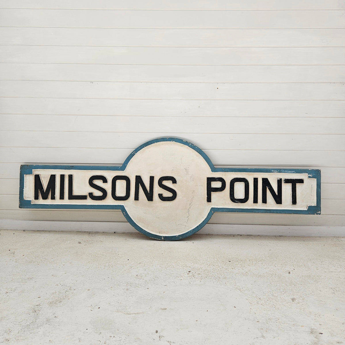 Round sign with &#39;MILSONS POINT&#39; text on a white background